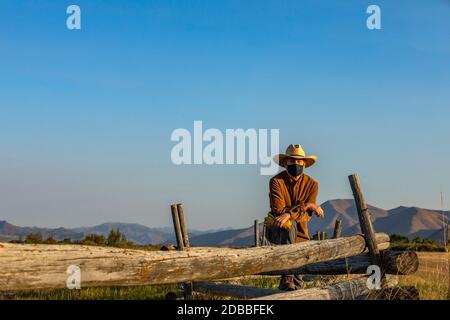 USA, Idaho, Bellevue, Rancher in Gesichtsmaske gegen Zaun auf dem Feld gelehnt Stockfoto