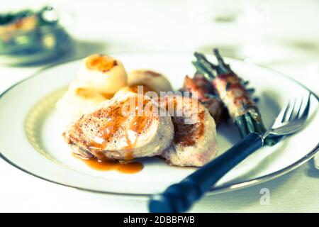 Schweinsmedaillons mit Kartoffeln und Bohnen in Speck gewickelt. Stockfoto