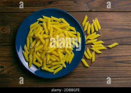 Pene Lisce Pasta in blauer Platte auf dunklem Holzhintergrund. Tolle Aussicht. Stockfoto