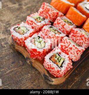 Zwei verschiedene Arten von Sushi-Rollen auf einem Holzbrett. Japanische Küche. Selektiver Fokus Stockfoto