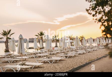 Leere Liegen am Sandstrand am Meer. Ort für Urlaub. Sonnenuntergang über dem leeren Strand Stockfoto