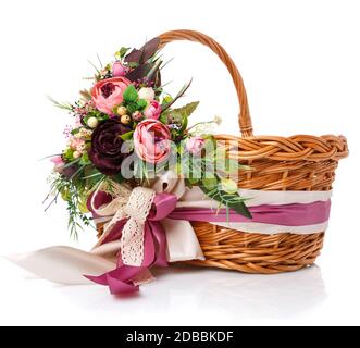 Schöne Blumenapposition mit violetten Blumen, Grün und Bändern, die am Griff eines Korbflechts auf weißem Hintergrund hängen Stockfoto