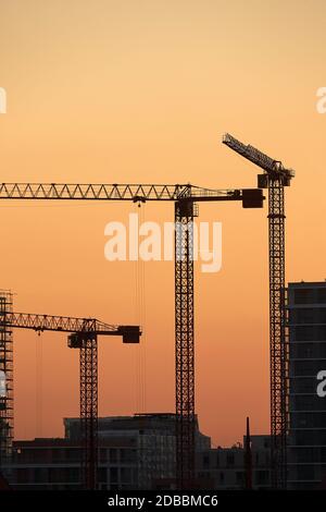 Baukräne gegen dramatische Dämmerung rot glühenden Himmel Stockfoto