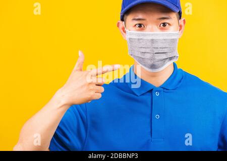 Asiatische junge Lieferung Arbeiter Mann in blauen T-Shirt und Mütze Uniform tragen Gesichtsmaske Schutz verwenden Finger zeigen er Gesichtsmaske unter Coronavirus oder COV Stockfoto