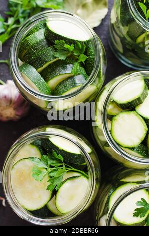 Erhaltung Zucchini und frischem Gemüse für den Winter. In Scheiben geschnittene Zucchini mit Petersilie und Knoblauch, hausgemachte Gemüse konserviert in Glas Glas Stockfoto