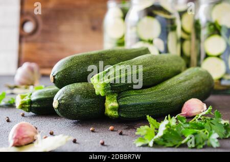 Frische organische Zucchini, Knoblauch und Petersilie, Kräutern und Gewürzen. Prozess der Home Erhaltung von Zucchini in Töpfen Stockfoto