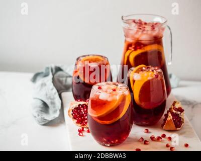 Wintersangria auf Tischplatte mit grauer Leinentischdecke. Juggly von Sangria und Gläser mit Obstscheibe, Cranberry und Rosmarin. Kopieren Sie den Bereich für den tex Stockfoto