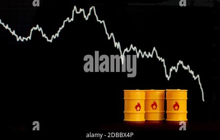 Barrel Öl und Benzin auf dem Hintergrund eines Bildschirms mit einem fallenden Diagramm. Stockfoto