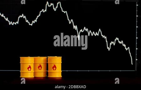 Barrel Öl und Benzin auf dem Hintergrund eines Bildschirms mit einem fallenden Diagramm. Stockfoto