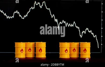 Barrel Öl und Benzin auf dem Hintergrund eines Bildschirms mit einem fallenden Diagramm. Stockfoto