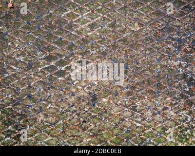 Vollbildansicht einer rostigen, abgenutzten und verwitterten Bodenplatte mit abblätternder Farbe. Stockfoto