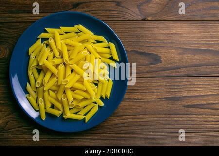 Pene Lisce Pasta in blauer Platte auf dunklem Holzhintergrund. Top-Ansichten mit viel Platz. Stockfoto