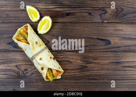 Döner wickeln Kebab. Shawarma mit Fleisch, Zwiebeln, Salat liegt auf einem dunklen alten Holztisch. Top-Ansichten mit viel Platz. Stockfoto