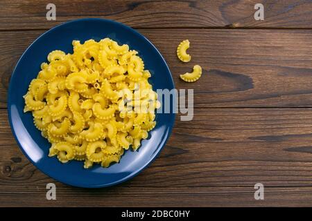 Pene Lisce Pasta in blauer Platte auf dunklem Holzhintergrund. Top-Ansichten mit viel Platz. Stockfoto