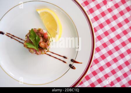 TARTARE DI TONNO O SALMONE. Fein gewürfelter Thunfisch und Lachs mit Schalotte, Zitronensaft, nativem Olivenöl extra und gehackten Kräutern gemischt. Serviert mit Salat Stockfoto