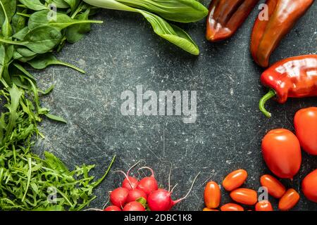 Verschiedene Gemüse. Rucola, Radieschen, Spinat, Paprika, Tomaten und pak Choi auf dem Küchentisch. Draufsicht. Stockfoto