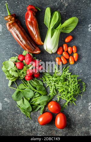Verschiedene Gemüse. Rucola, Radieschen, Spinat, Paprika, Tomaten und pak Choi auf dem Küchentisch. Draufsicht. Stockfoto
