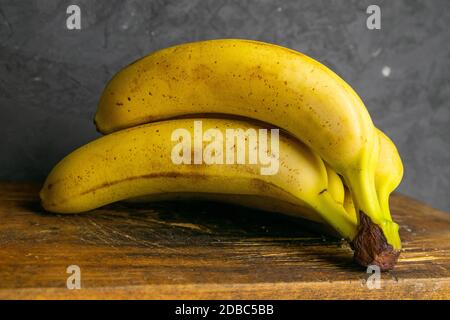 Drei Bananen liegen auf alten Holzbrettern. Nahaufnahme. Stockfoto