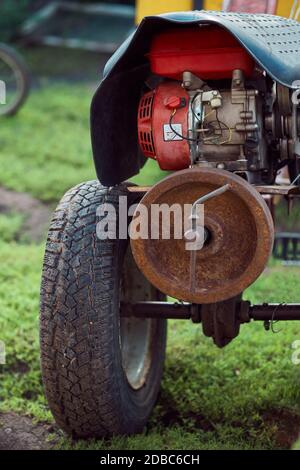 Motor und Rad des modernen begehbaren Traktors auf Gras geparkt Rasen im Hof in der Landschaft Stockfoto