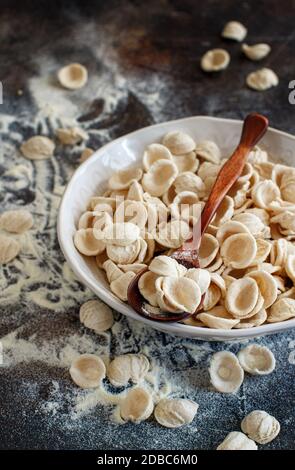 Frische rohe apulische Pasta Orecchiette aus Vollkornmehl auf einem dunklen Tisch aus nächster Nähe Stockfoto