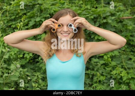 Junge schöne Brünette Mädchen lächelt und Narren herum mit bewegen Spinner in den Händen im Sommer Stockfoto