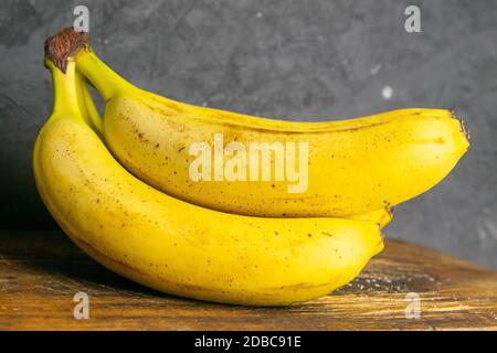 Drei Bananen liegen auf alten Holzbrettern. Nahaufnahme. Stockfoto