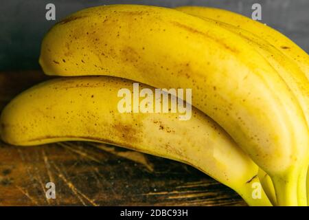 Drei Bananen liegen auf alten Holzbrettern. Nahaufnahme. Stockfoto