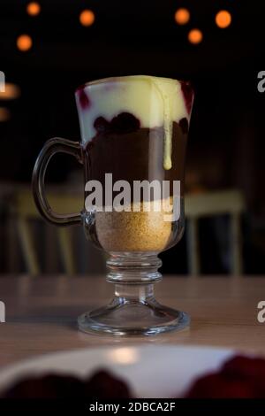 Heiße Schokolade mit Schlagsahne, Himbeeren und Gemahlenen Keksen am Tisch im Restaurant Stockfoto