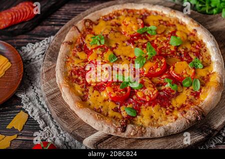 Rustikale hausgemachte Pizza mit scharfem Cheddar Chesse und würziger Salami Stockfoto