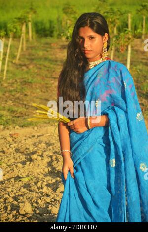 Close up Indian Bengali Teenager schönes Mädchen trägt blauen Sari und goldfarbenen Schmuck wie Ohrringe, Halskette, Armreifen mit langen dunklen Haaren Stockfoto