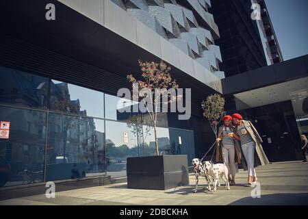 Minsk, Weißrussland - 30.04.2018 - zwei Zwillingsmädchen in roten Berets laufen mit Hunden der Dolmatian-Rasse durch die Stadt. Stockfoto