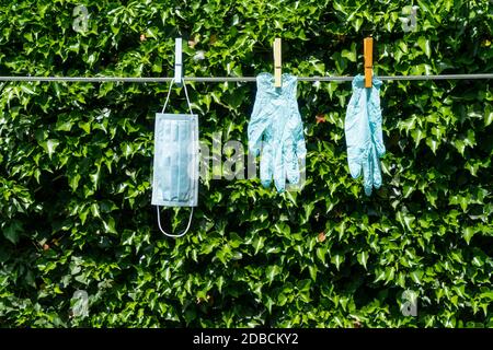 Eine Maske und ein Paar Handschuhe hängen an einem Draht im Garten Stockfoto