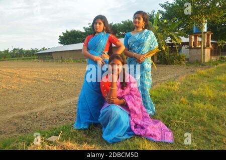 Drei Teenager-Mädchen im Dorf tragen traditionelle indische bengalische Kleidung und posieren für die Kamera in einem Dorf Feld, selektive Fokussierung Stockfoto