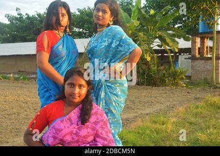 Drei Teenager-Mädchen im Dorf tragen traditionelle indische bengalische Kleidung und posieren für die Kamera in einem Dorf Feld, selektive Fokussierung Stockfoto