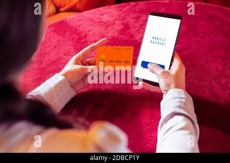 Menschliche Hand hält Smartphone mit Online-Shopping-App und Kreditkarte. Stockfoto