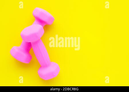 Blick von oben auf die rosa Hanteln auf gelbem Hintergrund. Platz kopieren Stockfoto