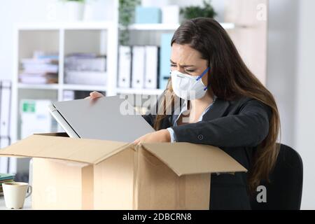 Traurig gefeuerte Exekutive Frau mit Schutzmaske weinend Verpackung ihre Sachen auf einer Kiste im Büro Stockfoto