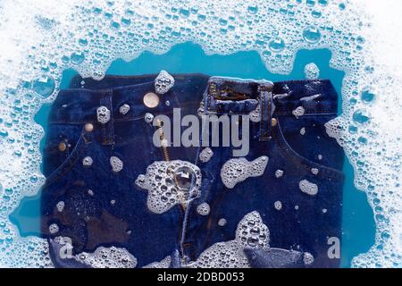 Jeans in Pulver Waschmittel Wasser Auflösung einweichen, waschen Tuch. Wäscheservice Konzept Stockfoto