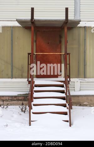 Rustikale Tür mit Treppen unter Schnee Stockfoto
