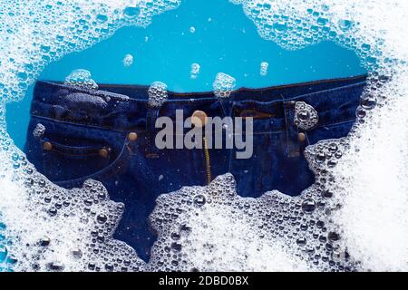 Jeans in Pulver Waschmittel Wasser Auflösung einweichen, waschen Tuch. Wäscheservice Konzept Stockfoto