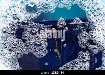 Jeans in Pulver Waschmittel Wasser Auflösung einweichen, waschen Tuch. Wäscheservice Konzept Stockfoto