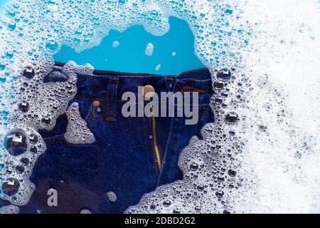 Jeans in Pulver Waschmittel Wasser Auflösung einweichen, waschen Tuch. Wäscheservice Konzept Stockfoto