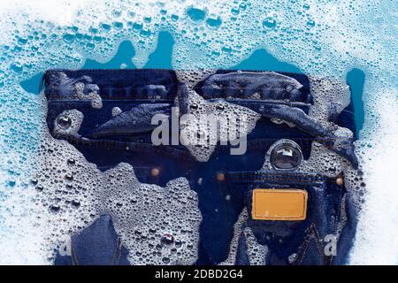 Jeans in Pulver Waschmittel Wasser Auflösung einweichen, waschen Tuch. Wäscheservice Konzept Stockfoto