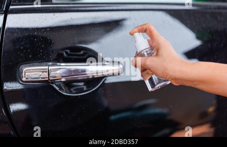 Asiatische junge Frau Anwendung Presse Spender Desinfektionsmittel Alkohol Spray spritzen, um Autotür waschen Reinigung, Hygiene-Prävention COVID-19 oder Coronavirus Protec Stockfoto