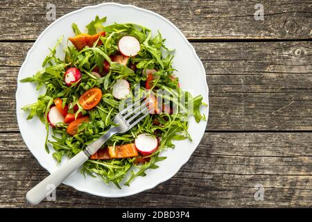 Frischer Rucola-Salat mit Radieschen, Tomaten und Paprika auf dem Teller. Draufsicht. Stockfoto