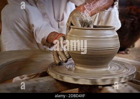 Indischer Töpfer bei der Arbeit: Das Töpferrad werfen und Keramikgefäß und Tonwaren Formen: Topf, Glas in Töpferwerkstatt. Erfahrener Meister. Handwor Stockfoto