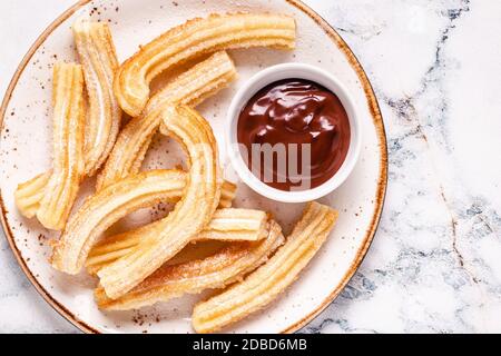 Churros mit Puderzucker und Schokoladensauce, Draufsicht. Stockfoto