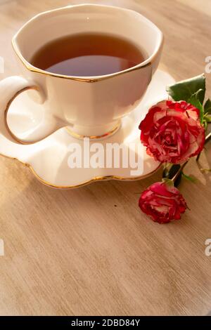 Tasse Tee in einer china-Tasse und Untertasse, auf einem verzweifelten Tisch und Rosen Stockfoto