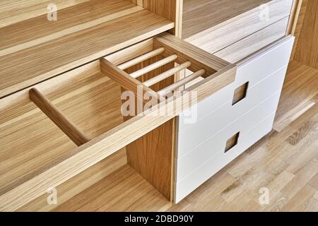 Interne Details der Holzgarderobe mit ausziehbarem Gestell für Kleiderständer. Eiche furnierte Sperrholzschränke mit hellgrau lackierten Schranktüren. Deta Stockfoto