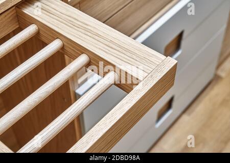 Interne Details der Holzgarderobe mit ausziehbarem Gestell für Kleiderständer. Eiche furnierte Sperrholzschränke mit hellgrau lackierten Schranktüren. Deta Stockfoto